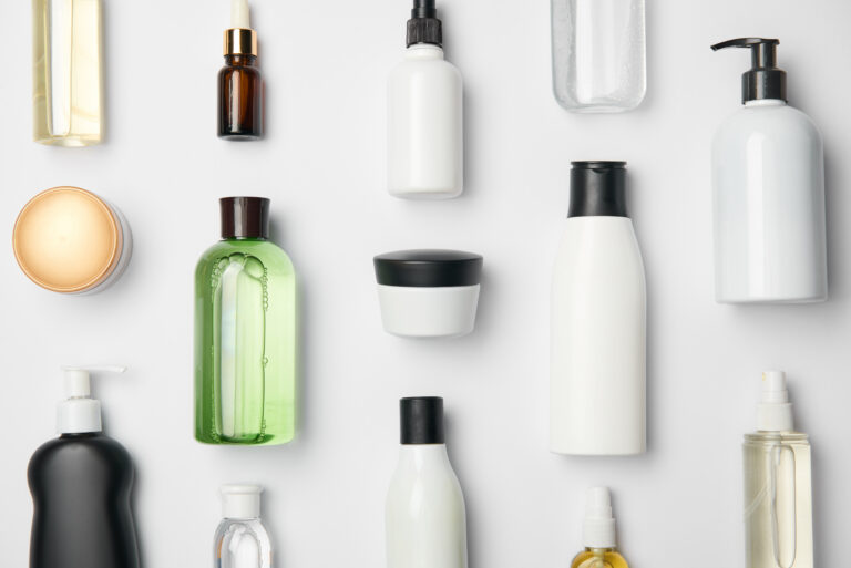 Top view of different cosmetic bottles and container on white ba